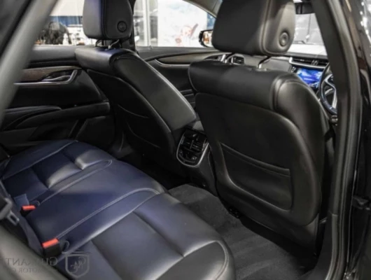View of the spacious rear passenger area of a Cadillac XTS featuring black leather seats and climate control vent