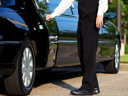 Chauffeur opening the door of a black luxury limousine.